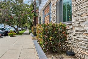 Long Beach apartment for rent - A stone building with a window and a bush in front.
