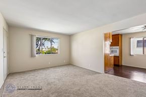 Inglewood apartment for rent - A spacious room with a carpeted floor and a window overlooking trees.