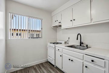 Hawthorne apartment for rent - A kitchen with white cabinets and a window with blinds.