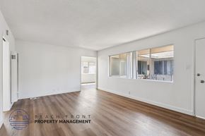 San Pedro apartment for rent - A spacious room with wooden floors and a large mirror on the wall.