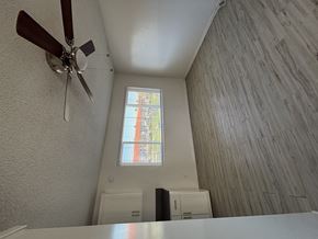 Long Beach apartment for rent - A ceiling fan hangs over a white table in a room with a window.