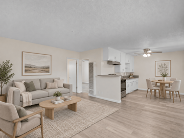 Long Beach apartment for rent - A living room with a grey couch, a wooden coffee table, and a dining table with chairs.