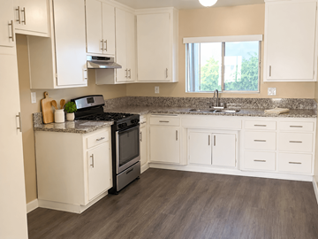 Long Beach apartment for rent - A kitchen with white cabinets and a black stove top oven.