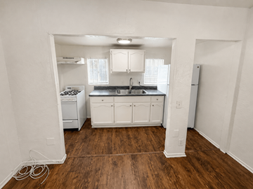 Signal Hill apartment for rent - A kitchen with white cabinets and a wooden floor.