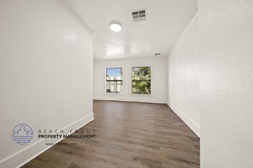 Wilmington apartment for rent - A spacious room with wooden flooring and a window overlooking a green area.