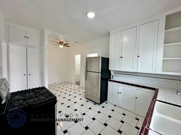 San Pedro apartment for rent - A kitchen with white cabinets and a black fridge.