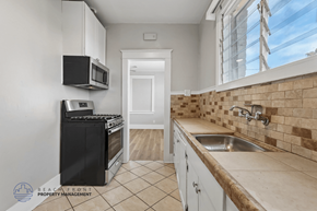 Long Beach apartment for rent - A kitchen with a black oven and microwave, a sink, and a tiled backsplash.