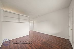Hawthorne apartment for rent - A room with wooden floors and white walls, with a logo for Beach Front Property Management in the bottom left corner.