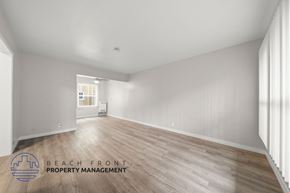 Long Beach apartment for rent - A spacious room with wooden flooring and white walls, managed by Beach Front Property Management.