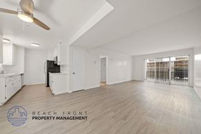 Santa Monica apartment for rent - A spacious room with a ceiling fan and a logo for Beach Front Property Management.