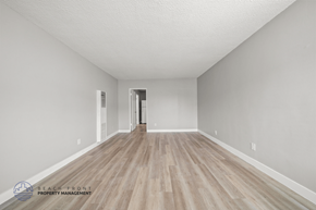 Inglewood apartment for rent - A spacious room with wooden flooring and white walls, with a doorway leading to another room.