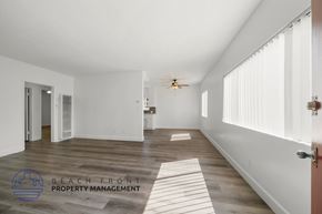 Inglewood apartment for rent - A spacious room with wooden flooring and white walls, with a logo for Beach Front Property Management in the bottom left corner.
