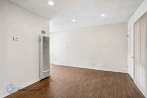 Downey apartment for rent - A spacious room with a wood floor and a wall-mounted air conditioning unit.