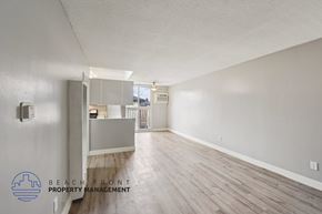 Alhambra apartment for rent - A spacious room with wooden flooring and a logo for Beach Front Property Management in the corner.