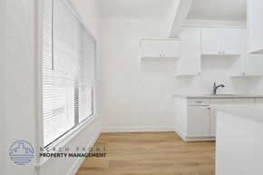 Long Beach apartment for rent - A kitchen with white cabinets and a wooden floor.