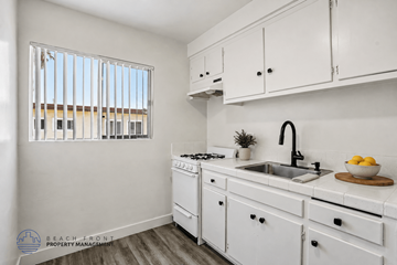 Hawthorne apartment for rent - A kitchen with white cabinets and a window with blinds.
