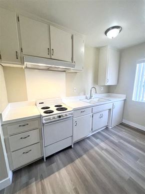 La Habra apartment for rent - A white kitchen with a stove, sink, and cabinets.