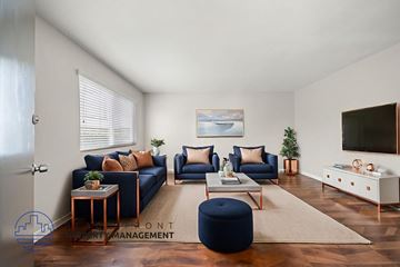 Stanton apartment for rent - A living room with a blue ottoman and a television on the wall.
