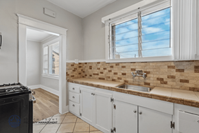Long Beach apartment for rent - A kitchen with white cabinets and a brown tile backsplash.