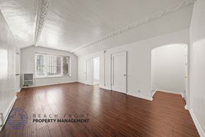 Los Angeles apartment for rent - A spacious room with wooden floors and white walls, with a window and a door visible.
