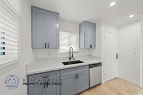Redondo Beach apartment for rent - A kitchen with a sink and cabinets with a logo for Beach Front Property Management.