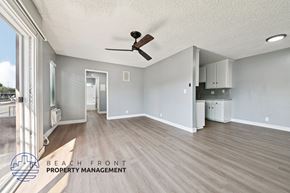Santa Ana apartment for rent - A spacious room with a ceiling fan and a logo for Beach Front Property Management.