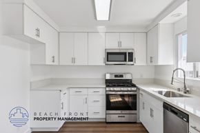 San Pedro apartment for rent - A kitchen with white cabinets and appliances, with the logo of Beach Front Property Management in the bottom left corner.