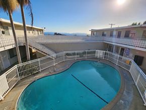 San Pedro apartment for rent - A swimming pool surrounded by a white fence and palm trees.