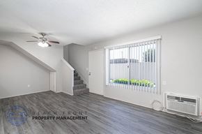 Anaheim apartment for rent - a living room with a large window and a ceiling fan