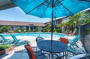 Anaheim apartment for rent - a table with chairs and an umbrella next to a swimming pool