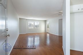 Whittier apartment for rent - A spacious room with wooden floors and white walls, with a door on the left and a window on the right.