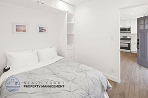 Huntington Beach apartment for rent - A bedroom with a bed, nightstand, and a wall-mounted shelf.