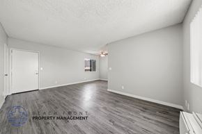 Los Angeles apartment for rent - A spacious room with wooden flooring and a logo for Beach Front Property Management in the corner.
