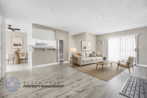 Wilmington apartment for rent - A spacious living room with a kitchen area in the background and a logo for Beach Front Property Management in the bottom left corner.