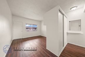 Hawthorne apartment for rent - A room with wooden floors and white walls, with a window showing a view of a building outside.