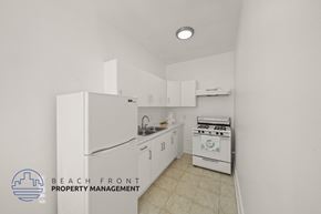 Los Angeles apartment for rent - A kitchen with white appliances and cabinets, with a logo for Beach Front Property Management in the bottom left corner.