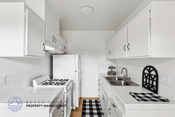 Hawthorne apartment for rent - A kitchen with white cabinets and a black and white checkered mat on the counter.