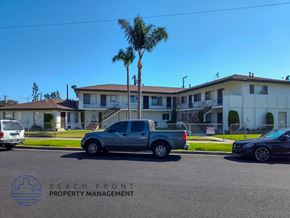 Garden Grove apartment for rent - a building with palm trees and a truck parked in a parking lot