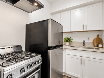 Long Beach apartment for rent - A black refrigerator sits next to a stove in a kitchen with white cabinets.
