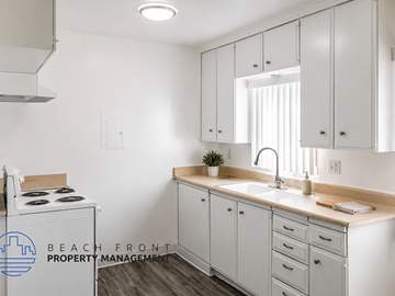 Long Beach apartment for rent - A kitchen with white cabinets and a stove top oven.