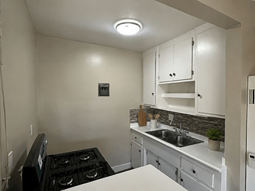 Anaheim apartment for rent - A small kitchen with a black stove top and white cabinets.