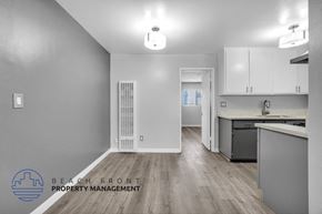 Long Beach apartment for rent - a renovated kitchen and living room with white cabinets and wood flooring