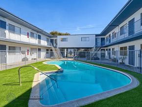Downey apartment for rent - A swimming pool in front of a white building with a metal fence around it.