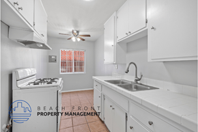 Long Beach apartment for rent - a kitchen with white cabinets and a sink and a stove