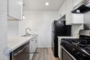 Newport Beach townhouse for rent - A kitchen with a black fridge and stove top oven.