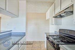 Long Beach apartment for rent - A kitchen with a stove top oven and a logo for Beach Front Property Management.