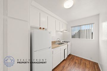 Hawthorne apartment for rent - A kitchen with white cabinets and a refrigerator with a logo of Beachfront Property Management.