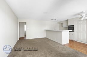 Wilmington apartment for rent - A spacious room with a carpeted floor and a logo for Beach Front Property Management in the corner.