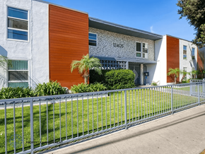 Downey apartment for rent - A modern building with a grey and orange facade and a metal fence in front.