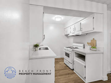 Inglewood apartment for rent - A kitchen with white cabinets and appliances, with the logo of Beach Front Property Management in the bottom left corner.